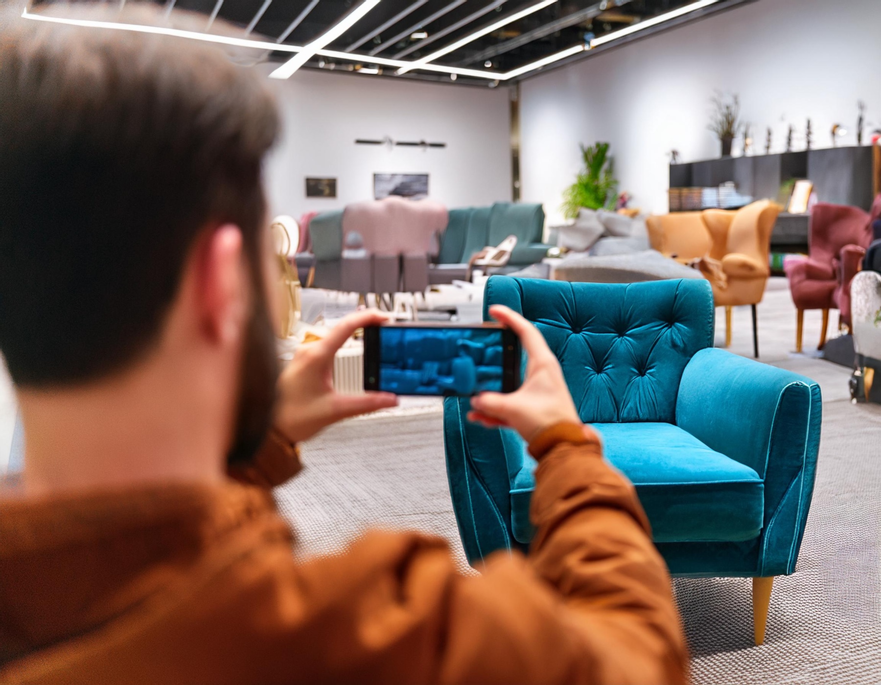 A man taking an image of a chair in a home furnishings store with his mobile phone.